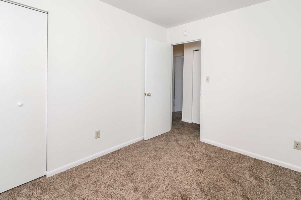 Hickory Hill Townhome bedroom number 2 view from the farthest corner looking at the door into the hallway White walls and chocolate colored carpet