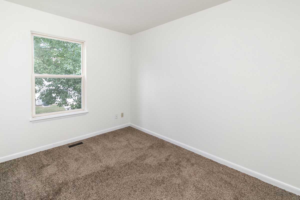Hickory Hill Townhomes bedroom number 2, view from doorway looking in at window on back wall. White walls and chocolate colored carpet