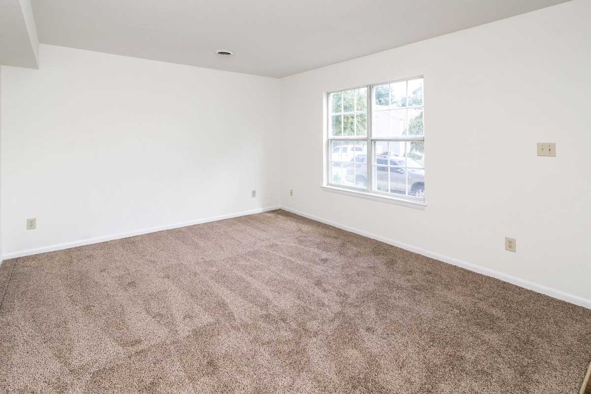 Hickory Hill living room, view of front picture window. White walls, chocolate colored carpet