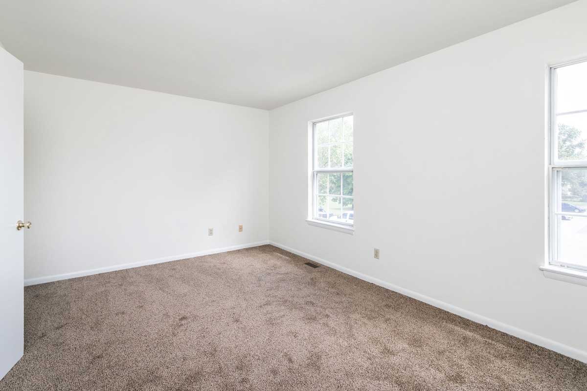 Hickory Hill Master bedroom view from door, in picture are 2 windows, chocolate carpet, white walls,