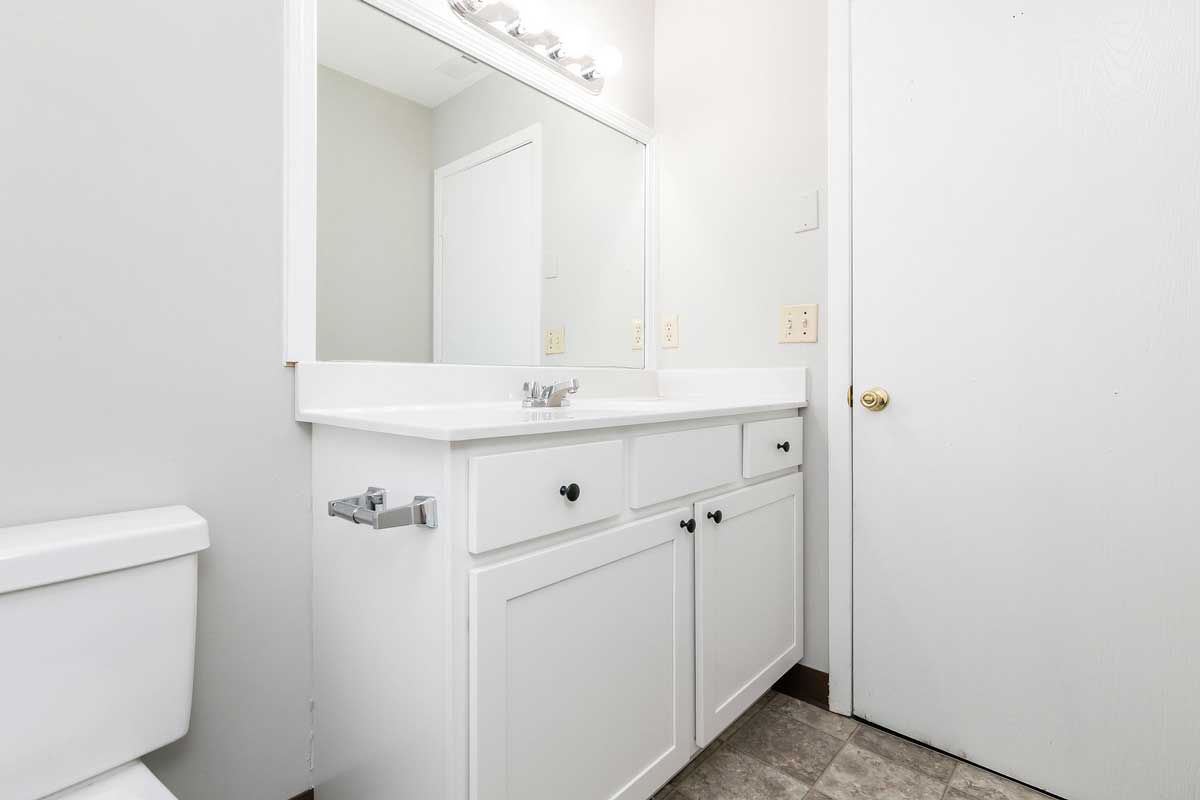 Township house bathroom view of white sink vanity cabinet with black hardware, Vanity cabinet has two drawers and under sink storage